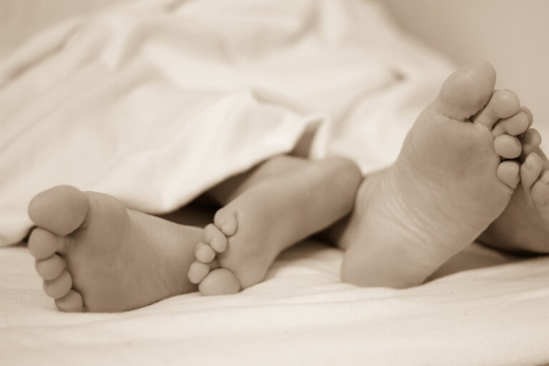 intimate couple in bed wrapped in quilt